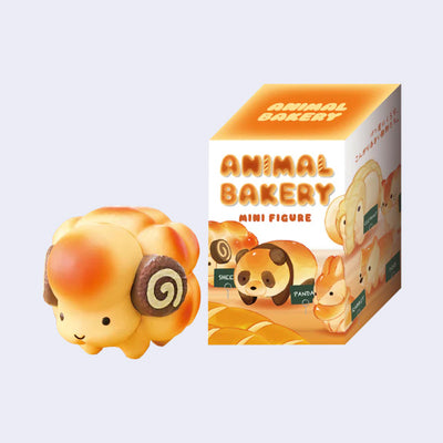 Small vinyl figure of a sheep made out of bread, with a golden brown color on his baked body and small swiss rolls for horns. It stands next to its product packaging.