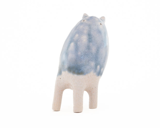 Ceramic sculpture of a small blue and white creature with small ears and eyes and no arms but 4 legs.