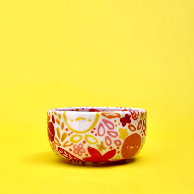 Small ceramic bowl, white with many paintings of floral patterns and fruits in warm colors such as orange, red, yellow and pink.