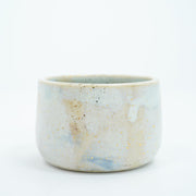 Short ceramic bowl with a light blue and cream multicolor glaze and golden splatters.