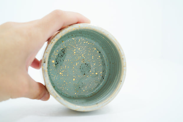 Inside view of ceramic bowl, a mint green color with gold speckles.
