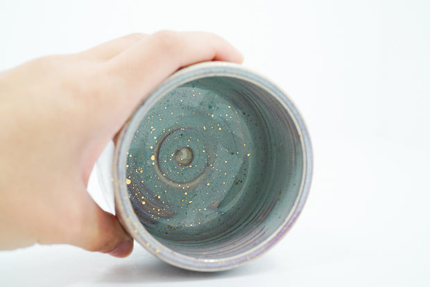 Inside view of ceramic bowl with blueish green coloring and gold speckles.