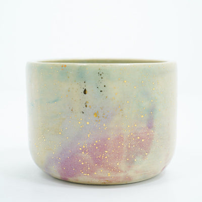 Short ceramic bowl with a light green and light purple multicolor glaze and golden splatters.