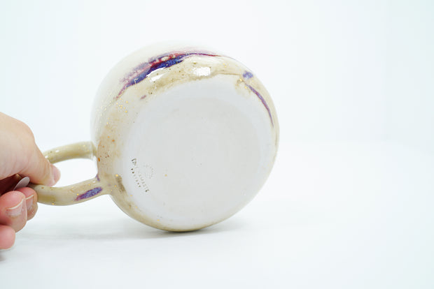 Underside of ceramic mug, unglazed with artist's signature stamped into the clay.