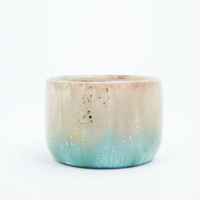 Small ceramic cup with a gradient of light brown to blue and gold speckles.