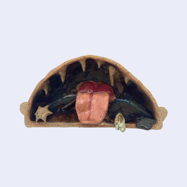 Ceramic sculpture of the interior of a monster's mouth, made to look like an underwater cave. It has a pink tongue and teeth that look like stalactites.   