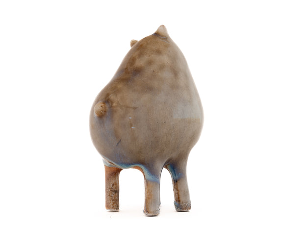 Ceramic sculpture of a brown character with a rounded body, small ears and eyes and skinny legs and no other body features.