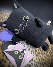 Black plush sculpture of a flat cat, with a purple beret and a vinyl sleeved record at its feet that reads "Cool for Cats." Its posed resting on its side.