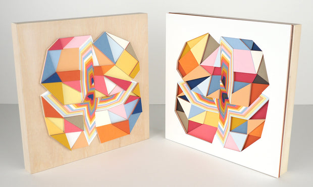 Geometric designed layered cut paper sculpture, creating a three dimensionality. A vertical and horizontal cross section of a 10 sided shape reveals many layers. Colors are earthy toned browns, oranges, yellows, blues and reds. Shown with its partner.