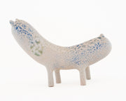 Ceramic sculpture of a long bodied, skinny character with small ears and eyes standing on 4 short legs.