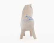 Ceramic sculpture of a long bodied, skinny character with small ears and eyes standing on 4 short legs.