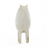 Ceramic sculpture of a light tan character with small ears, eyes and 4 legs. It has curved handle liked shapes overlapping on its back.