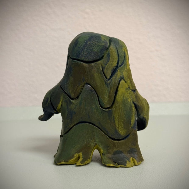 Sculpture of Hedorah, a pollution smoke monster, dark blue and yellowish green. It stands on 2 slimey legs and has large red eyes.
