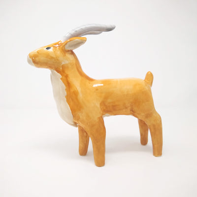 Ceramic sculpture of a orange tan elk, with long grey horns and subtle facial features.