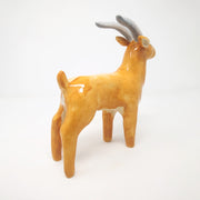 Ceramic sculpture of a orange tan elk, with long grey horns and subtle facial features.