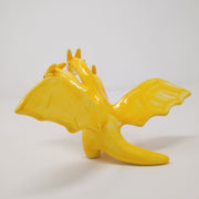 Yellow glazed ceramic sculpture of a 3 headed dragon, with wings spread out. The heads each have soft horns and minimal facial features, with only eyes.