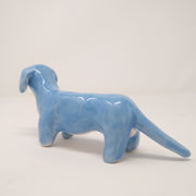 Backside of a blue ceramic sculpture of a Dachshund with a long tail.