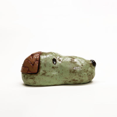 Ceramic sculpture of a green dog head, akin to Snoopy without the ears. His brain is exposed and can be removed to reveal the inside.