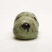 Ceramic sculpture of a green dog head, akin to Snoopy without the ears. His brain is exposed and can be removed to reveal the inside.