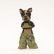 Ceramic sculpture of a Boston Terrier standing wearing a black crop top and baggy jeans. It has its arms folded across its chest.