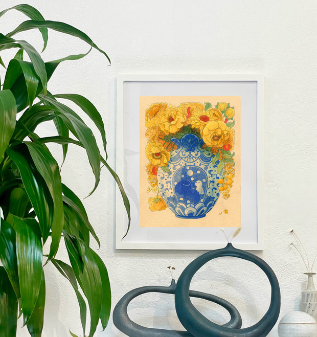 Illustration of a blue vase with ornate patterning and a central image of a large blob with a simplistic round headed character, sitting next to one another. Coming out the vase are many large yellow flowers. Piece is in a white frame.