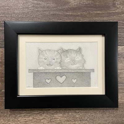Framed graphite illustration of 2 cute cartoon cats sitting in a box with hearts on the exterior.