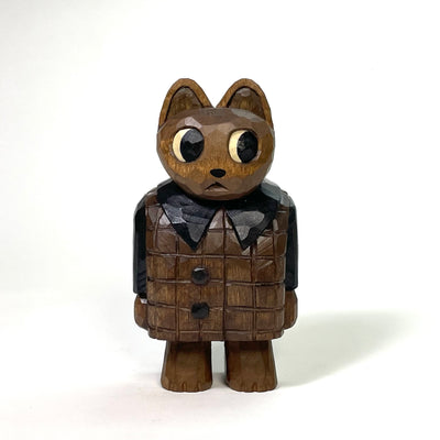 Stained whittled wood sculpture of a cartoon cat, looking off to the side and wearing a puffy coat with a grid pattern and black collar, sleeves and buttons. It stands on 2 legs with its arms to its side.