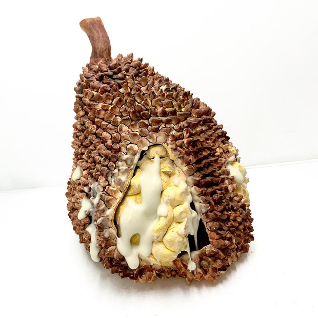 Ceramic sculpture of a durian, partially open to reveal the yellow fruit inside with white sticky substances dripping down it.