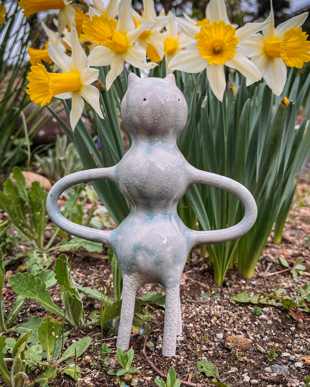 Ceramic sculpture of a character with a body made of 3 spheres stacked atop one another. Its arms are like mug handles.