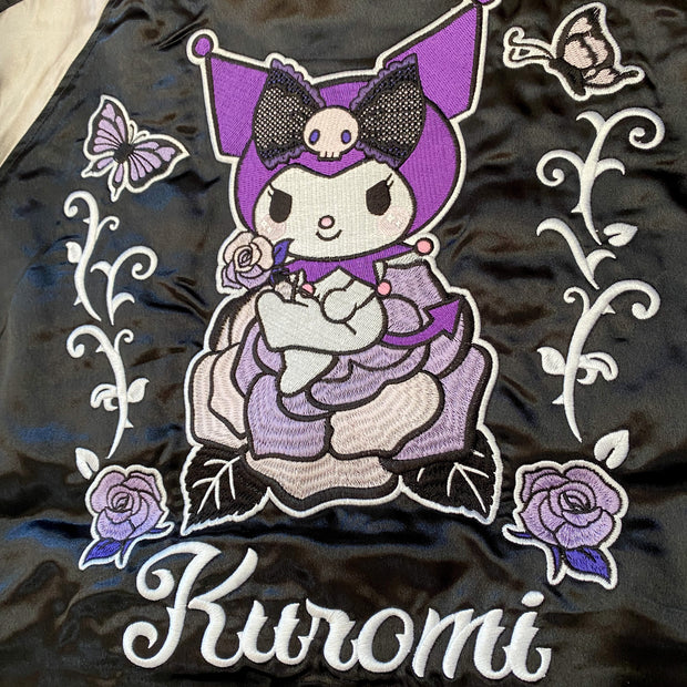 Close up of a large embroidered graphic of Kuromi sitting on a purple rose with more roses and butterflies next to her.