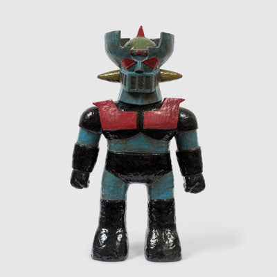 Stoneware sculpture of a robot with a blue body and black metal clothing. It has a red chest piece and red eyes and detailing.