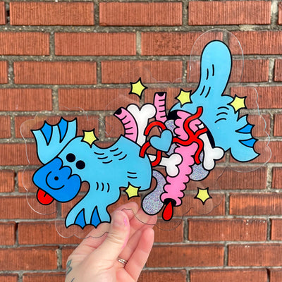 Painting on a die cut piece of clear acrylic of a blue cartoon platypus, split in half with its guts and bones coming out.