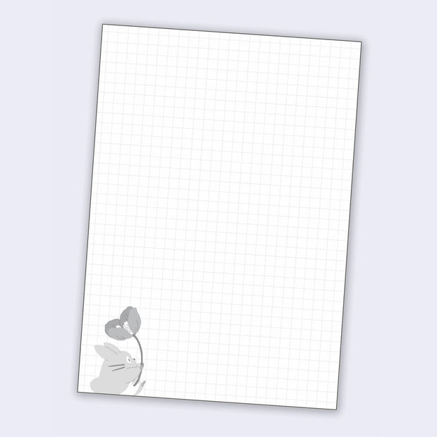 Page sample, graph paper with a small gray illustration of a small totoro holding a flower.
