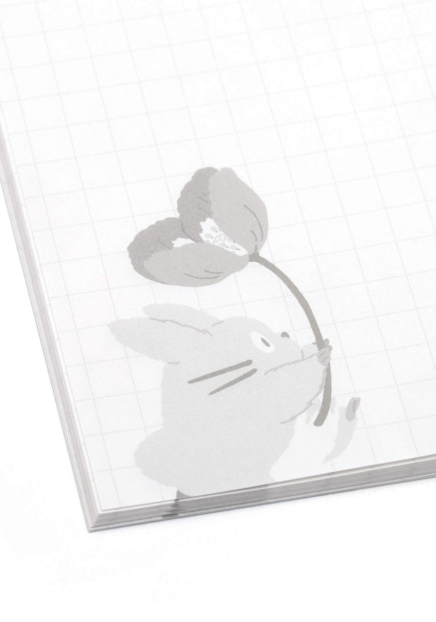 Page sample, graph paper with a small gray illustration of a small totoro holding a flower.