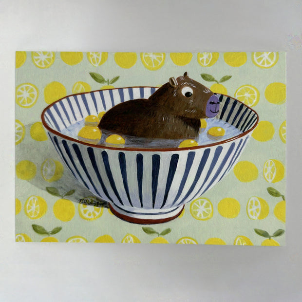 Illustration of a capybara sitting in a bowl with water and small lemons. Background is a pattern of lemons.