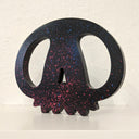 Black wooden sculpture of a skull, with large eye sockets and rounded nubs for teeth.