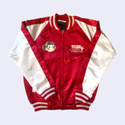 Shiny polyester bomber jacket with red body and white sleeves.  Front has 2 small embroidered graphics on the chest, right side is text that reads "Milky, the nature goodness of milk from us to you" and the other side is an embroidery of Peko Chan's face.