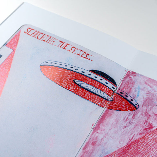 Page close up, of a UFO illustration and text that reads "searching the skies."