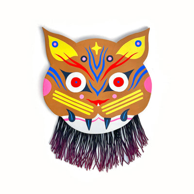 Brightly painted wooden die cut sculpture of a brown cat with fierce, folk art style decoration. It has purple strands hanging from its chin.