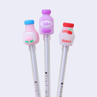 3 pens with plastic pen toppers shaped like yogurt drink containers. One is pink and says "peach", another is purple with lettering in another language, and the last is white with red accents and a cherry.
