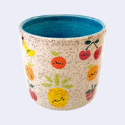 Ceramic planter with spotted finishing and an earthy cream exterior and teal interior. On the outside are painted on cartoon style fruits, with simple expressions.