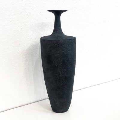 Tall black vase with a skinny neck and fluted opening.
