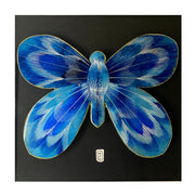 Cut out illustration of a vibrant blue butterfly with abstract striping pattern on its wings, adhered to black paper. Butterfly has gold outlining.