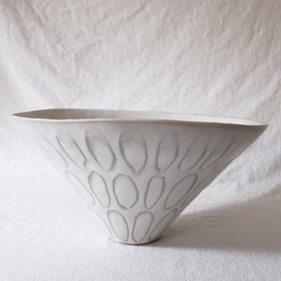 Large white bowl with slightly crooked top and many ovals all around it as a pattern.