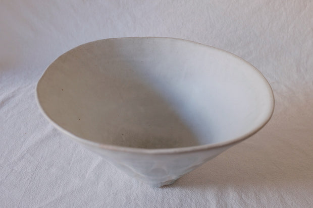 Large white bowl with slightly crooked top and many ovals all around it as a pattern.