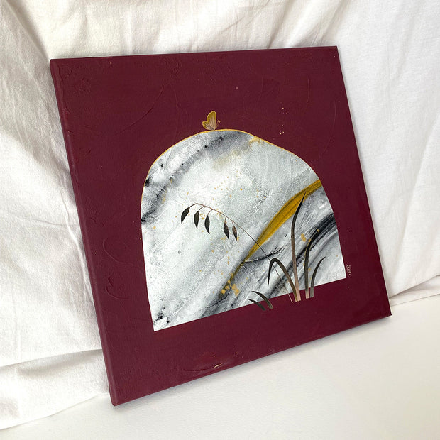 Collage style painting on solid burgundy canvas of a grey marble patterned rock with gold streaks. A small gold butterfly sits atop the rock and blades of tall grass stand in the right corner. Displayed at an angle.