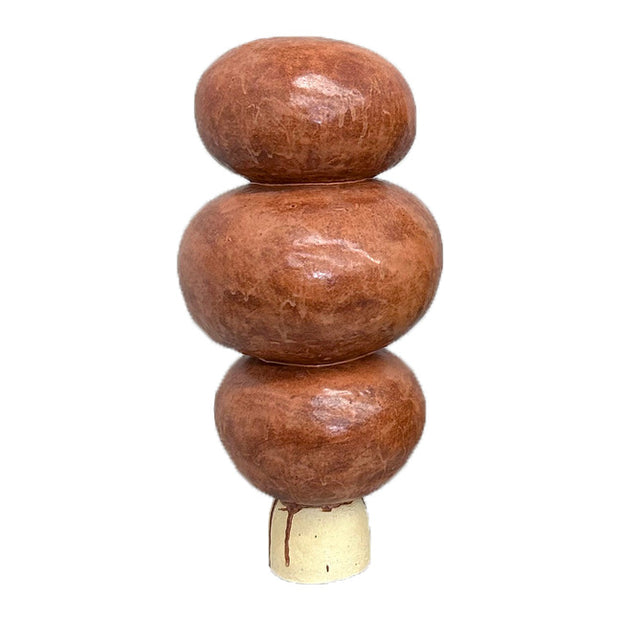 Ceramic sculpture of a tree comprised of 3 orange rounded shapes stacked atop one another with a thin trunk.