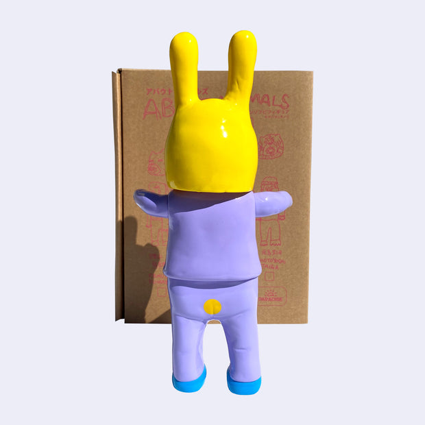 Back view of Satoshi Yamamoto figure, as he wears a lilac suit with a small hole cut out on the seat of his pants, showing his butt cheeks slightly. Atop his head is a large yellow rabbit mask.