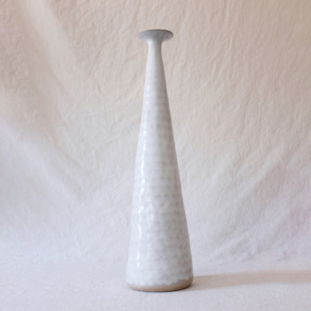 Very tall ceramic vase with skinny, fluted top. Vase is white with very faint gray dots.