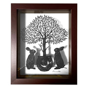 Paper cutting art from black paper, of 2 rabbits standing on their hind legs around a potted tree, with many individual leaves. Piece is in a thick wooden shadowbox frame.
